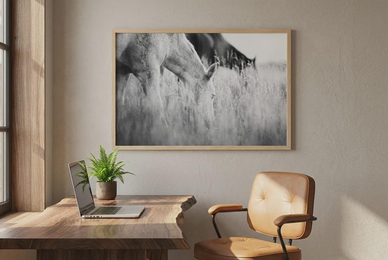 Pu&ograve; includere: Stampa incorniciata in bianco e nero di due cavalli al pascolo in un campo. L'opera d'arte &egrave; esposta sopra una scrivania in legno con un laptop e una felce in vaso. Una sedia in pelle marrone si trova nelle vicinanze.