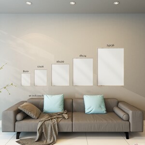 May include: A living room interior with a gray couch and five framed pictures on the wall. The pictures are in different sizes, with the largest being 24x36 inches. The couch is 96 inches long and has two pillows on it.