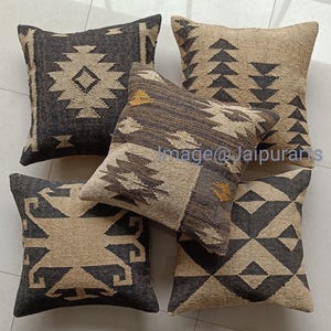 Puede incluir: Cuatro cojines decorativos con patrones geométricos en tonos negros, marrones y beige. Los cojines están hechos de tejido tejido y tienen un estilo rústico y bohemio.