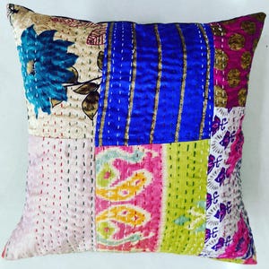 May include: A patchwork pillow cover with a variety of colors and patterns, including blue, pink, green, and gold. The cover is made of silk and is quilted with intricate stitching.