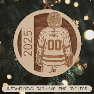 May include: Wooden hockey ornament with a laser-cut design. The ornament features a hockey player's jersey with the number 00 and space for a name. The year 2025 is displayed on the left side. The ornament is round with a hole for hanging.