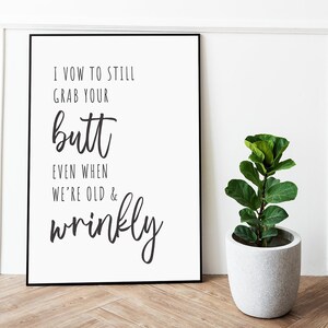 Könnte beinhalten: Ein schwarz-weiß gerahmter Druck mit dem Text "I vow to still grab your butt even when we're old & wrinkly". Der Druck hängt an einer weißen Wand mit einer grünen Pflanze in einem grauen Topf im Vordergrund.