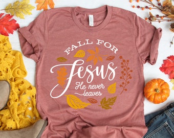 May include: A maroon t-shirt with the text "Fall for Jesus He never leaves" in white lettering surrounded by a circle of fall leaves.