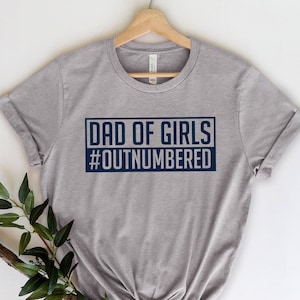 May include: A heather gray t-shirt with a navy blue graphic that says "Dad of Girls #Outnumbered".