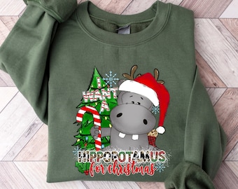 May include: Green Christmas sweatshirt with a cartoon hippopotamus wearing a Santa hat and holding a candy cane. The text on the sweatshirt reads "I want a hippopotamus for Christmas".