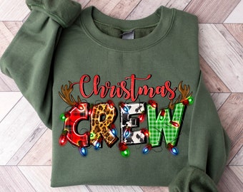 May include: A green sweatshirt with the words "Christmas Crew" in colorful letters with a plaid, leopard, and cow print design. The letters are surrounded by red, green, and white Christmas lights.