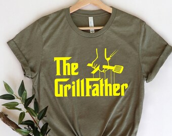 May include: A green t-shirt with a yellow graphic that says "The Grillfather" with a cartoon hand holding a spatula and a fork.