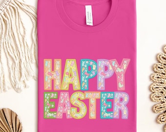 May include: Pink t-shirt with the text "HAPPY EASTER" in rainbow colors. Each letter is filled with a pattern of pastel colored bunnies and flowers.