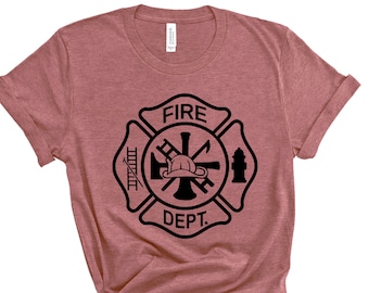 May include: A dusty rose t-shirt featuring a black firefighter Maltese cross design. The design includes a ladder, axe, helmet, and fire hydrant, with the words "FIRE DEPT." in a circular layout. The shirt is knotted at the bottom.