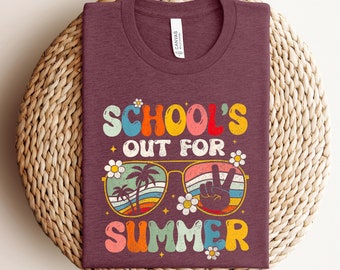May include: A maroon t-shirt with the text "School's Out For Summer" in colorful retro lettering. The text is surrounded by a pair of sunglasses with palm trees and a peace sign.