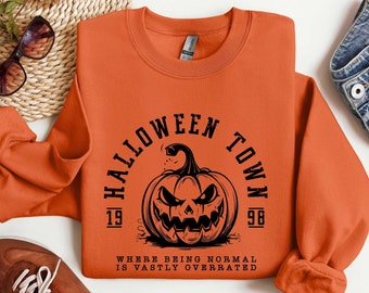 May include: Orange sweatshirt with a black graphic of a pumpkin with the text "Halloween Town 1998" and the phrase "Where being normal is vastly overrated".