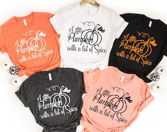 May include: Five t-shirts in different colors with the text "A little pumpkin with a lot of spice" and a pumpkin graphic. The shirts are all short-sleeved and crew neck.