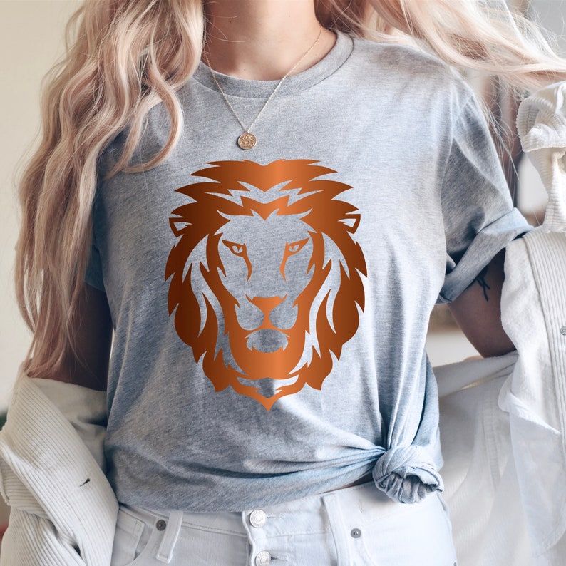 May include: A gray t-shirt with a copper-colored lion head graphic.