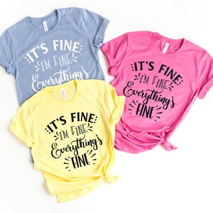 Peut inclure: Trois t-shirts de couleurs diff&eacute;rentes avec le texte "IT'S FINE: IM FINE Everything's FINE" imprim&eacute; dessus.