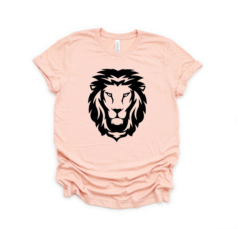 May include: A peach-colored t-shirt with a black silhouette of a lion's head.