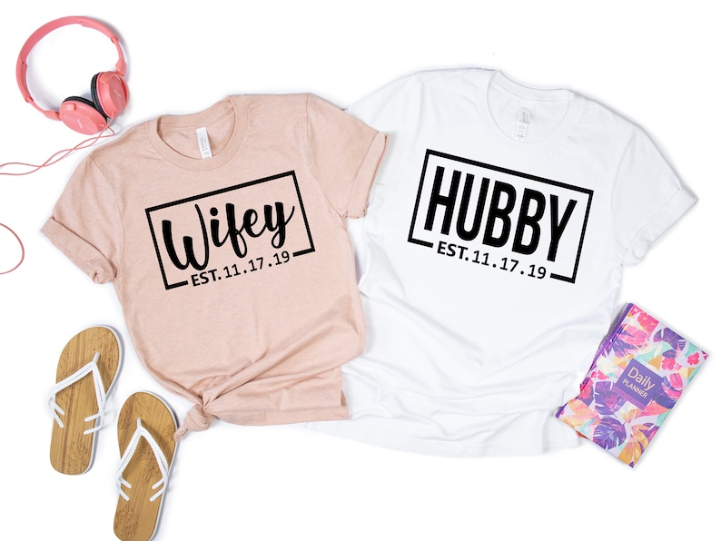 May include: Two t-shirts, one pink and one white, with the text "Wifey - EST. 11.17.19" and "Hubby - EST. 11.17.19" printed on them.