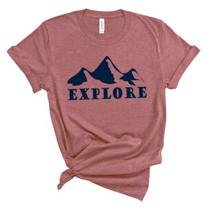 May include: A maroon t-shirt with a navy blue mountain silhouette and the word "EXPLORE" printed on the front.