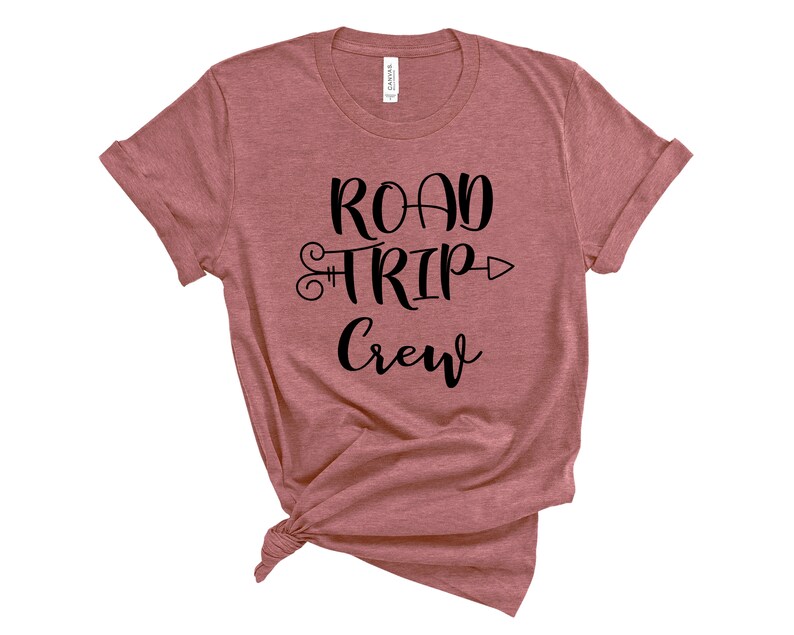 May include: A mauve t-shirt with the text "Road Trip Crew" in black lettering. The text includes a stylized arrow and a keyhole design.
