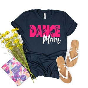 May include: A navy blue t-shirt with the text "Dance Mom" in pink letters. The word "Dance" is decorated with silhouettes of dancers.