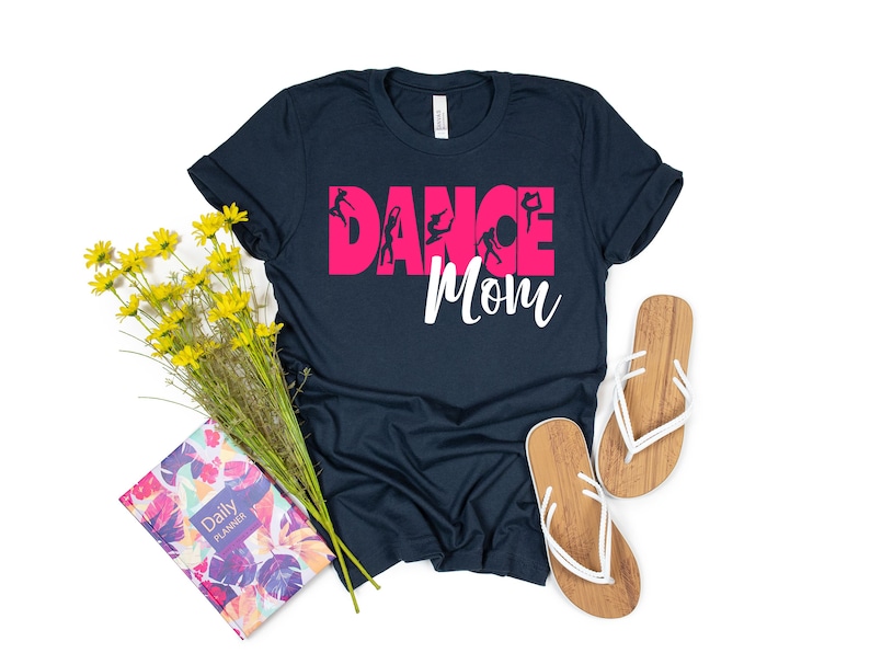 May include: A navy blue t-shirt with the text "Dance Mom" in pink letters. The word "Dance" is decorated with silhouettes of dancers.