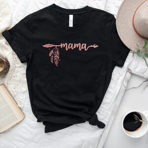 May include: Black t-shirt with a pink arrow and feather design and the word "mama" written in cursive.