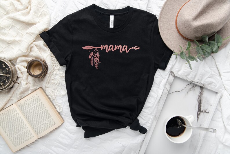 May include: Black t-shirt with a pink arrow and feather design and the word "mama" written in cursive.