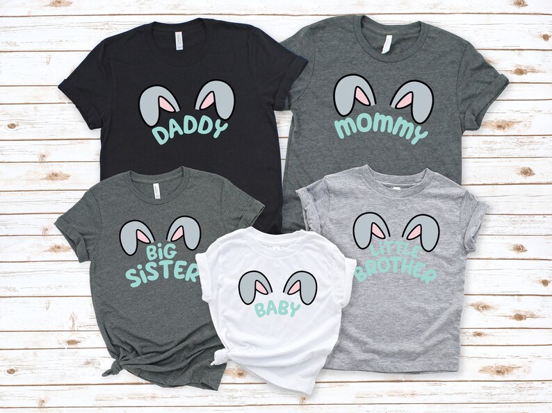Pu&ograve; includere: Un set di cinque t-shirt con orecchie di coniglio e testo. Le magliette sono di colore grigio, nero e bianco. Il testo sulle magliette recita "Pap&agrave;", "Mamma", "Sorella Maggiore", "Fratello Minore" e "Baby".