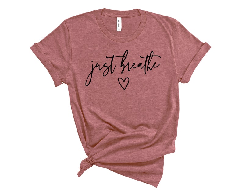 Puede incluir: Una camiseta de color malva con el texto "just breathe" en escritura negra con un peque&ntilde;o coraz&oacute;n debajo del texto.