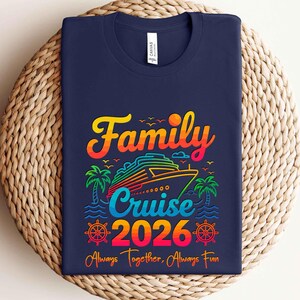 May include: Navy blue t-shirt with a colorful graphic design. The design features the words "Family Cruise 2026" with a cruise ship, palm trees, and the phrase "Always Together, Always Fun."