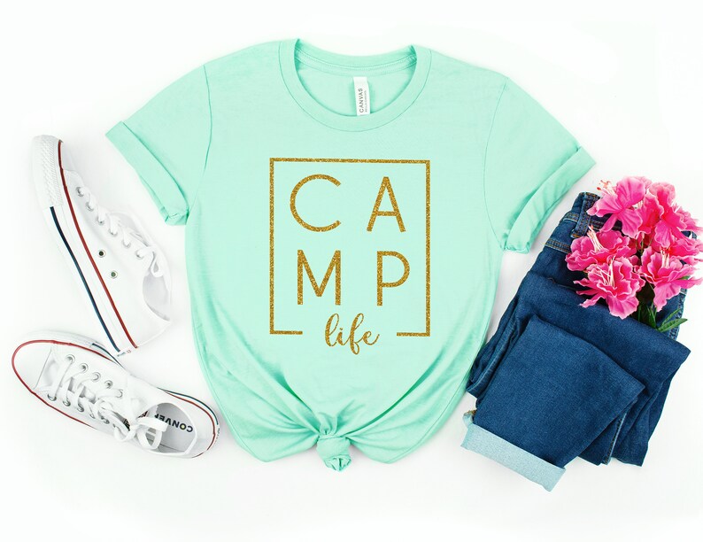 May include: A light green t-shirt with a gold glitter graphic that says "CAMP life" in a box.
