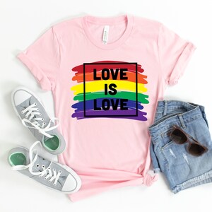 May include: Pink t-shirt with a rainbow graphic and the text "LOVE IS LOVE" in a black square.