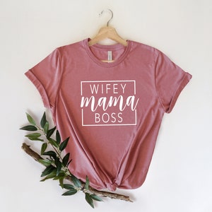 May include: A pink t-shirt with the text "WIFEY mama BOSS" in a white box.
