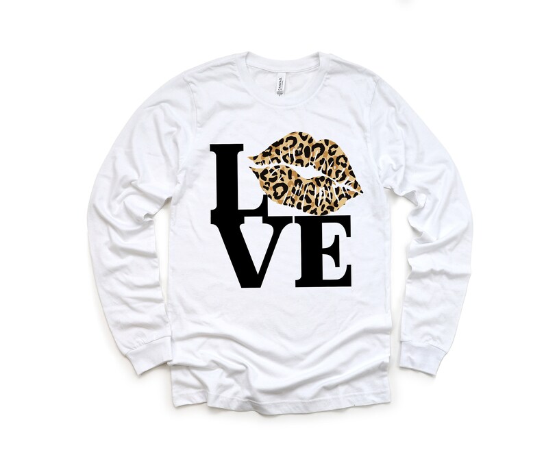 Pu&ograve; includere: Maglietta bianca a maniche lunghe con una grafica nera "LOVE" e un design a labbra con stampa leopardata.
