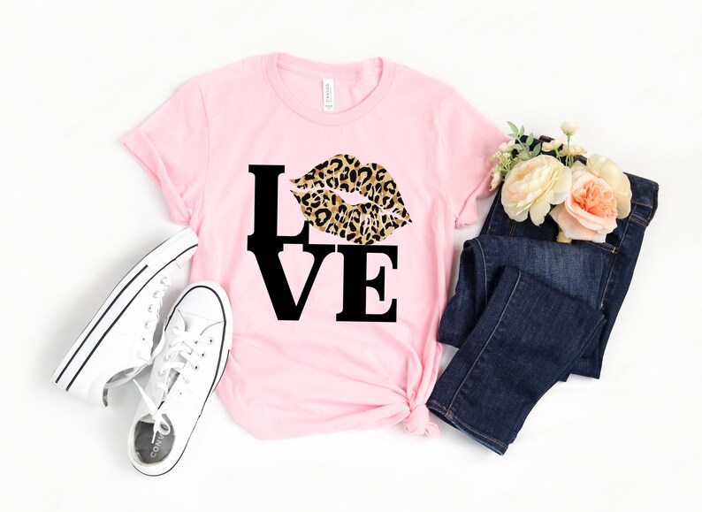 Pu&ograve; includere: Maglietta rosa con una grafica nera "LOVE" e un design a labbra con stampa leopardata.