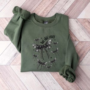 May include: A green sweatshirt with a black bat graphic and the text "bad shit crazy".