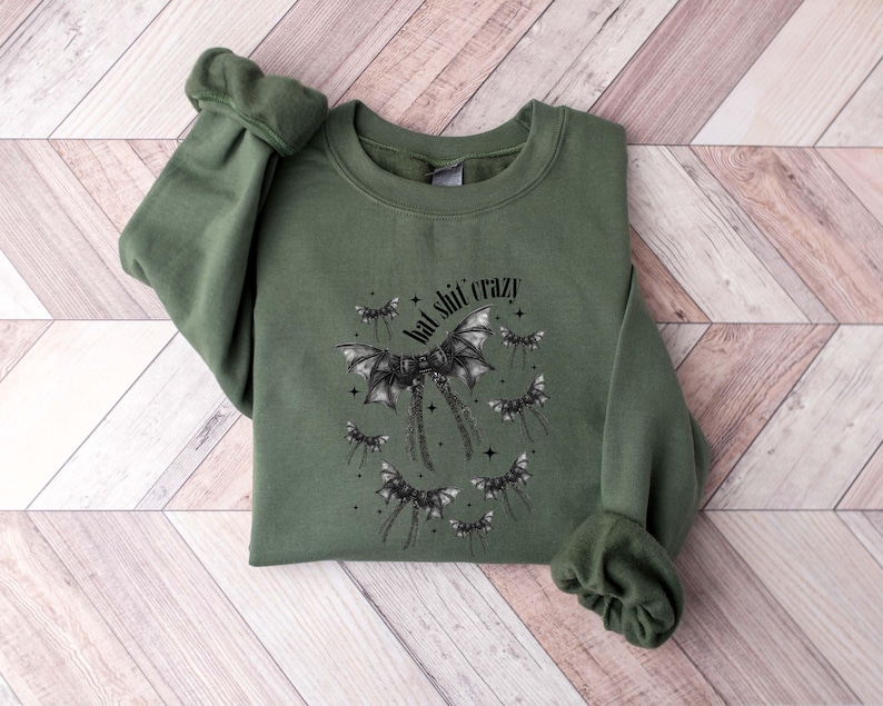 May include: A green sweatshirt with a black bat graphic and the text "bad shit crazy".