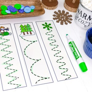 以下が含まれることがあります： 雪だるま、木、雪の結晶が描かれた、印刷可能ななぞり書きのワークシート3枚。各ワークシートには、緑色のマーカーでなぞるための点線があります。