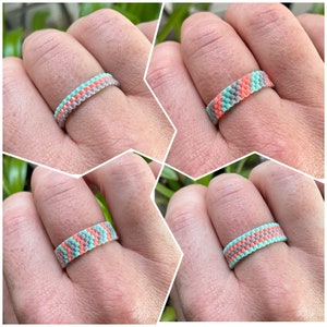 May include: A beaded ring with a pattern of gray, light blue, and coral beads.