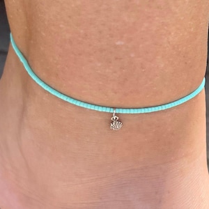 May include: A turquoise beaded anklet with a silver seashell charm.