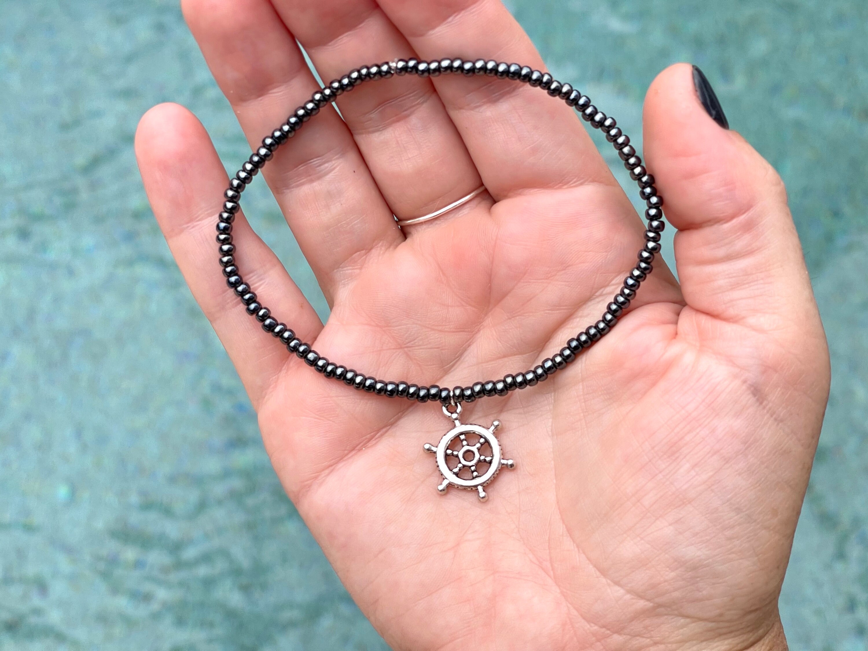 Cute stretchy anklet or bracelet made with 8/0 seed beads in your choice of color with a silver boat helm charm.