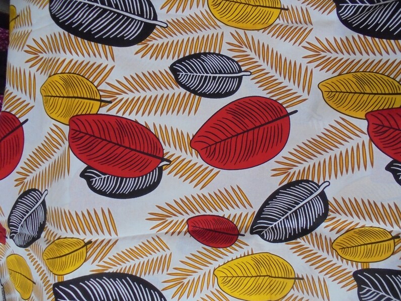 May include: White fabric with a repeating pattern of black, red, and yellow leaves. The leaves are stylized and have a graphic design.