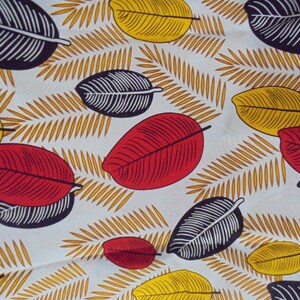 May include: A white fabric with a repeating pattern of black, red, and yellow leaves. The leaves are stylized and have a graphic design.