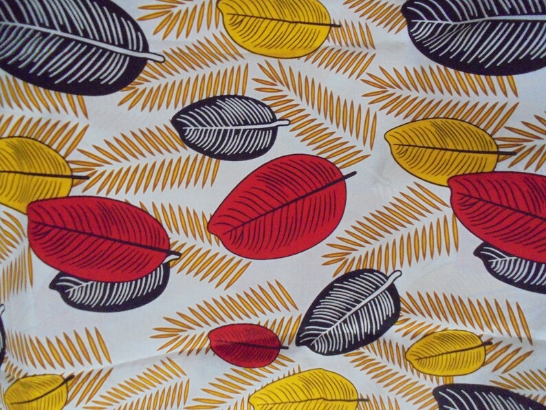 May include: A white fabric with a repeating pattern of black, red, and yellow leaves. The leaves are stylized and have a graphic design.