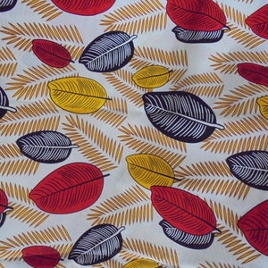 May include: White fabric with a repeating pattern of black, red, and yellow leaves. The leaves are stylized and have a graphic design.