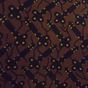 May include: A brown fabric with a repeating pattern of black and yellow stylized keys. The keys are arranged in a diagonal pattern.