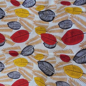 May include: White fabric with a repeating pattern of red, yellow, and black leaves. The leaves are stylized and have a simple design.