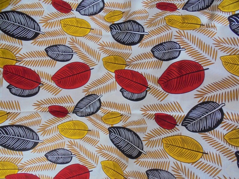 May include: White fabric with a repeating pattern of red, yellow, and black leaves. The leaves are stylized and have a simple design.