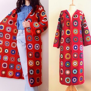 May include: A long red crochet cardigan with a colorful circular pattern. The cardigan has a hood and a front zipper.