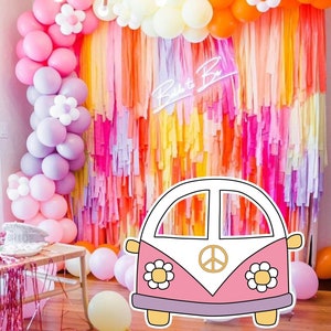 May include: A pink and white VW bus cutout with peace sign and flowers, in front of a colourful backdrop of tissue paper streamers and balloons. The text "Bride to Be" is in neon pink letters on the backdrop.