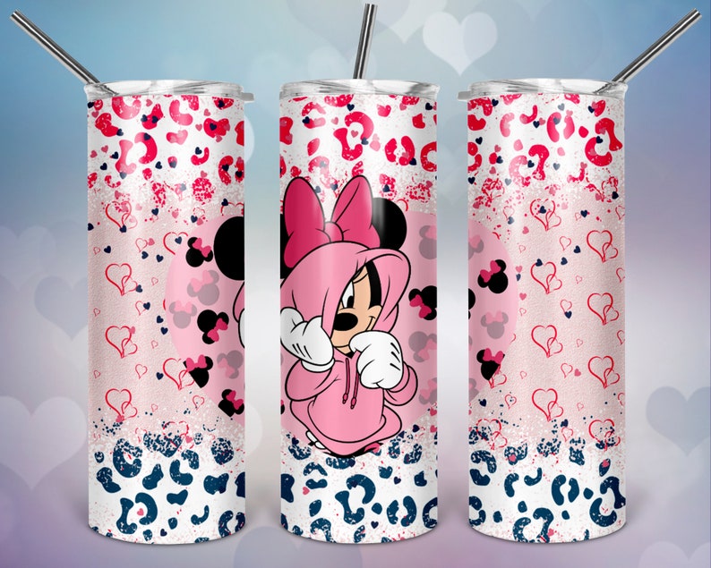 K&ouml;nnte beinhalten: Ein rosafarbener und wei&szlig;er Edelstahlbecher mit einer rosafarbenen Minnie Mouse, die ein rosafarbenes Hoodie und eine Schleife tr&auml;gt. Der Becher hat ein rosafarbenes und wei&szlig;es Leopardenmuster mit Herzen und Glitzer.